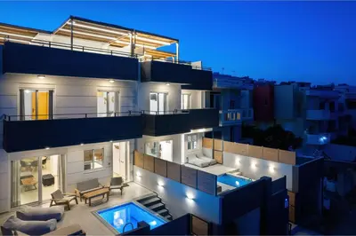 a apartment building with a swimming pool at night at ArmoniKon Pool Villas in Asgourou