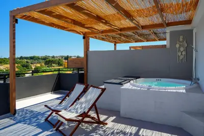 a deck with a chair and a hot tub at ArmoniKon Pool Villas in Asgourou