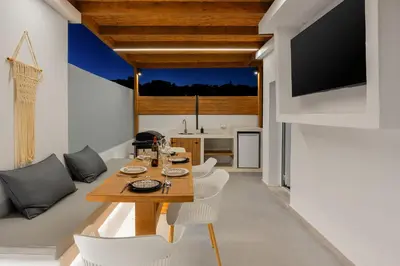 a dining room and kitchen with a table and chairs at ArmoniKon Pool Villas in Asgourou