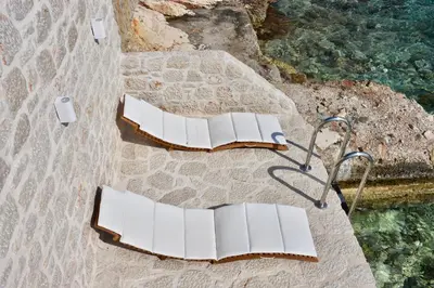two white chairs sitting on a beach next to the water at SALT RETREAT - Seafront Villa in Halki