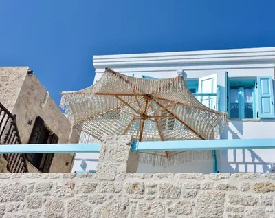 a beige umbrella sitting on top of a wall at SALT RETREAT - Seafront Villa in Halki
