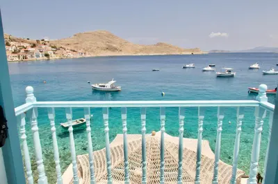a balcony with a view of a body of water with boats at SALT RETREAT - Seafront Villa in Halki