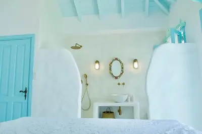 a white bedroom with a bed and a mirror at SALT RETREAT - Seafront Villa in Halki