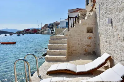 a group of white chairs sitting next to the water at SALT RETREAT - Seafront Villa in Halki