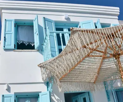 an umbrella in front of a white building with blue windows at SALT RETREAT - Seafront Villa in Halki