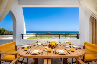 a wooden table with food and drinks on a balcony at Psychedelia Beach House in Gennadi
