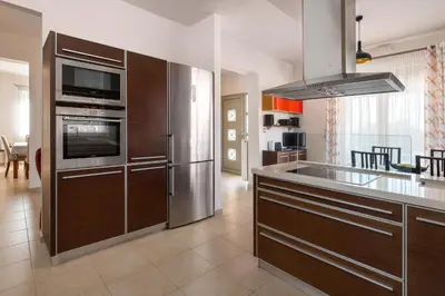 a kitchen with wooden cabinets and a stainless steel refrigerator at Cielo Blu villa in Soroni