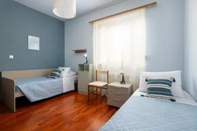 two beds in a bedroom with blue walls and wooden floors at Cielo Blu villa in Soroni