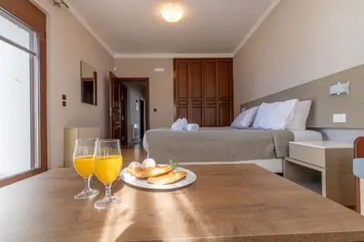 a room with a bed and a table with two glasses of orange juice at Onda Vista Luxury Villa in Kremasti