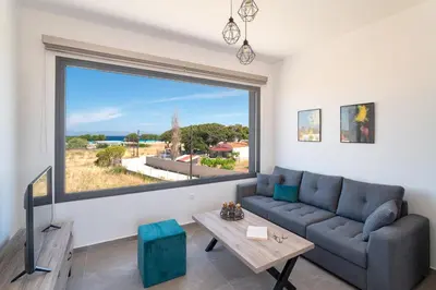 a living room with a couch and a large window at Lotus Luxury Apartments in Kremasti