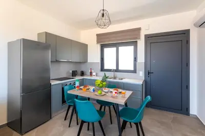 a kitchen with blue cabinets and a table and chairs at Lotus Luxury Apartments in Kremasti