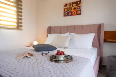 a bed with a tray of fruit and books on it at Lotus Luxury Apartments in Kremasti