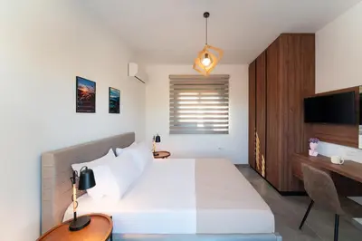a bedroom with a bed and a desk and a television at Lotus Luxury Apartments in Kremasti