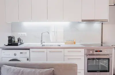 a white kitchen with a sink and a stove at Cozy Guesthouse in Koskinou