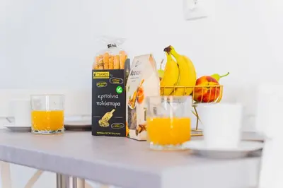 a table with orange juice and a basket of fruit at Cozy Guesthouse in Koskinou