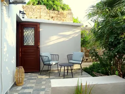 a patio with three chairs and a table and a door at Lilly's Cosy Studio in Rhodes Town