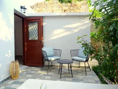 a patio with three chairs and a table and a door at Lilly's Cosy Studio in Rhodes Town