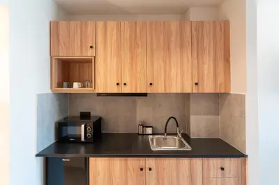 a kitchen with wooden cabinets and a sink and a microwave at Afesou Suites in Ialyssos