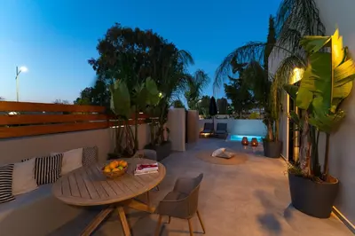 a patio with a table and chairs and plants at Afesou Suites in Ialyssos