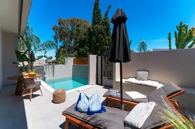 a patio with an umbrella and a swimming pool at Afesou Suites in Ialyssos