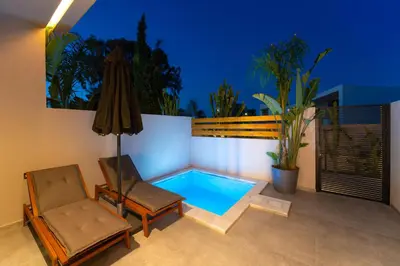 a small swimming pool with a chair and an umbrella at Afesou Suites in Ialyssos