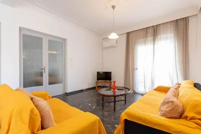 a living room with two yellow beds and a tv at Micasa Shiny Apartment in Rhodes Town