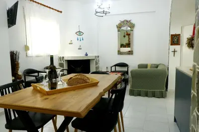 a dining room with a wooden table and a fireplace at Arco In Pietra in Apolakkiá