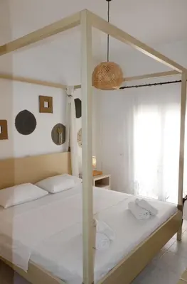 a bedroom with a canopy bed with white sheets at Arco In Pietra in Apolakkiá