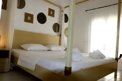 a bedroom with two beds with white pillows and a window at Arco In Pietra in Apolakkiá