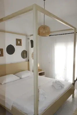 a bedroom with a canopy bed with white sheets at Arco In Pietra in Apolakkiá