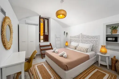 a white bedroom with a bed and a desk at Aelius Apartments in Symi