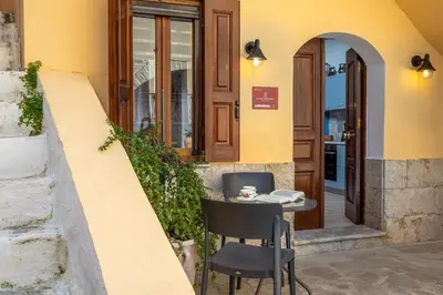 a small table and chair in front of a building at Aelius Apartments in Symi