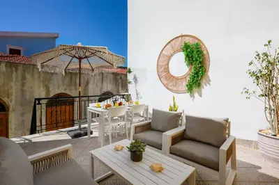 a patio with a table and chairs and an umbrella at Aelius Apartments in Symi