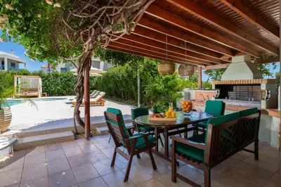 a patio with a table and chairs and a fireplace at Excelencia New Villa with Artistic Pool & Sea View in Asgourou