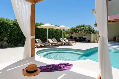 a pool with chairs and umbrellas and a hat on a table at Excelencia New Villa with Artistic Pool & Sea View in Asgourou