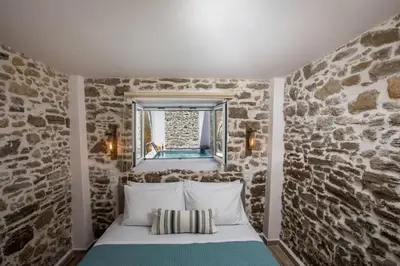 a bed in a room with a stone wall at Villa Gemma 2 next to Faliraki in Kalithies