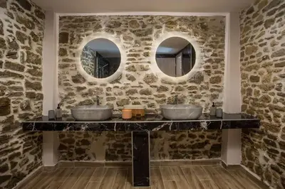 two sinks in a stone bathroom with two mirrors at Villa Gemma 2 next to Faliraki in Kalithies