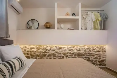 a bedroom with a bed and a stone wall at Villa Gemma 2 next to Faliraki in Kalithies