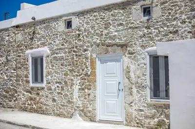 a stone building with a white door and windows at Villa Gemma 2 next to Faliraki in Kalithies
