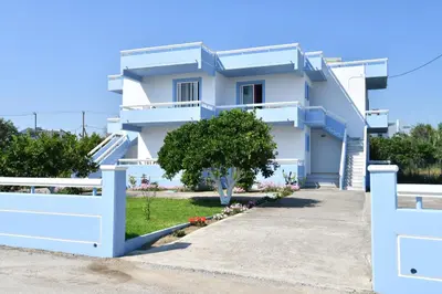a white house with a blue fence at Blue Serenity Apartment 5 in Ialyssos