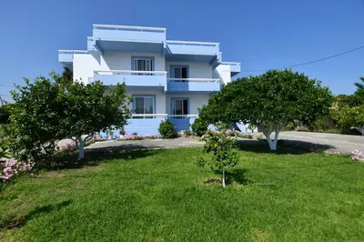 a white house with trees in front of it at Blue Serenity Apartment 5 in Ialyssos
