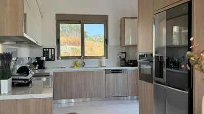 a kitchen with stainless steel appliances and a window at ARYVE Boutique Villa mit Akropolis- und Meerblick, Infinity-Pool und Designer-Interieur in Malona Village