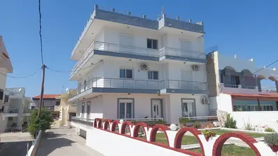 a white building with a red fence in front of it at George & Chrysi Apart in Kremasti