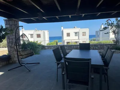 a table and chairs on a patio with the ocean at Villa Solmar Rhodes in Lachania