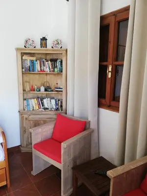a red chair in a room with a book shelf at Perla di Mare - Katoi 1 in Symi
