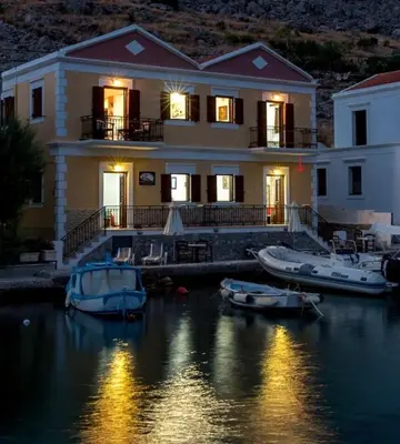 a house with boats docked in the water at night at Perla di Mare - Katoi 1 in Symi
