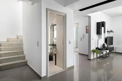 a hallway with white walls and white floors and a staircase at Niovis Villa in Pastida