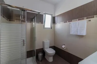 a bathroom with a toilet and a glass shower at Louka's House in Afantou