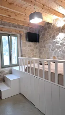 a room with white cabinets and a tv on a stone wall at Nisyros Nest in Nikiá