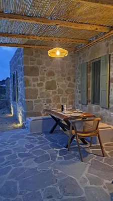 a wooden table and chairs on a stone patio at Nisyros Nest in Nikiá